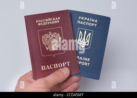 Ukrainian and Russian international passports in the man's hand. White background. Close up Stock Photo