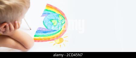 The child draws a planet of the world with rainbow and sun on the white paper.  Children's drawings, paintings and concepts. Education and art Stock Photo