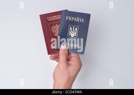 Ukrainian and Russian international passports in the man's hand. White background. Close up Stock Photo