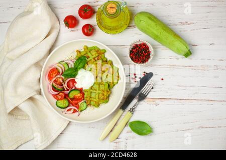 Delicious healthy green waffles with zucchini, spinach and Basil. It is served with a salad of fresh vegetables-tomatoes, cucumbers and red onions wit Stock Photo