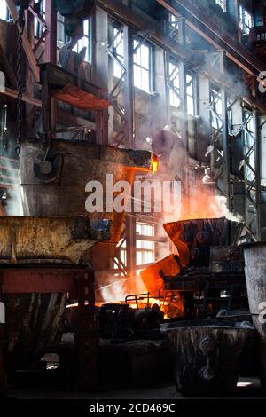 Metallurgy factory workshop. Melting of metal in processing. Red fire and white smoke or steam. Taraz city, Kazakhstan. Stock Photo
