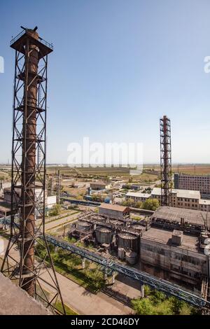 Old soviet metallurgy factory buildings and rusted chimneys and storage tanks on blue sky. Aerial view. Taraz city. Stock Photo