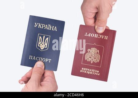 Ukrainian and Russian international passports in the man's hand. White background. Close up Stock Photo