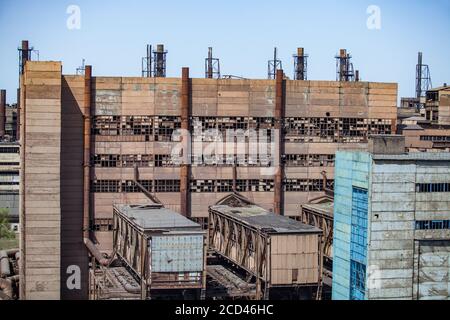 Old abandoned soviet metallurgy factory buildings with broken windows and rusted chimneys on the blue sky. Taraz city. Stock Photo