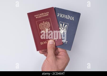 Ukrainian and Russian international passports in the man's hand. White background. Close up Stock Photo