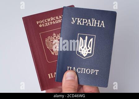 Ukrainian and Russian international passports in the man's hand. White background. Close up Stock Photo