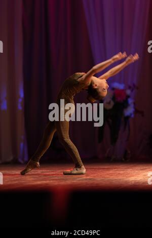 Young girl gymnast ballerina performs with a performance on stage in a theater Stock Photo