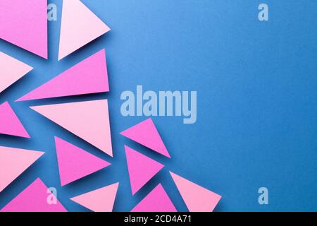 Pink triangular shapes in minimal creative style. Paper composition on blue background for presentations. Top view. Copy space Stock Photo