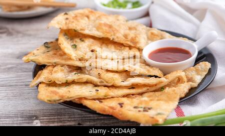 Taiwanese food - delicious flaky scallion pie pancakes on bright wooden table background, traditional snack in Taiwan, close up. Stock Photo