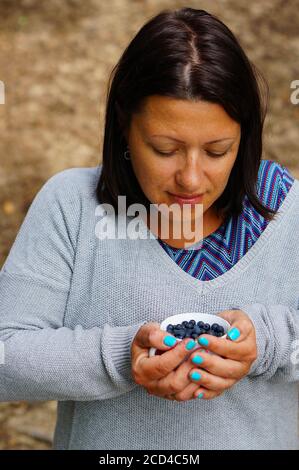 TLEN, POLAND - Aug 19, 2020: Brunette Polish Caucasian woman holding a bowl with fresh blueberrie Stock Photo