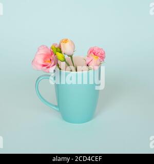 Creative concept made of coffee or tea cup with tender pink Eustoma flowers. light blue or turquoise background. Pink Eustoma flowers in the blue cup Stock Photo