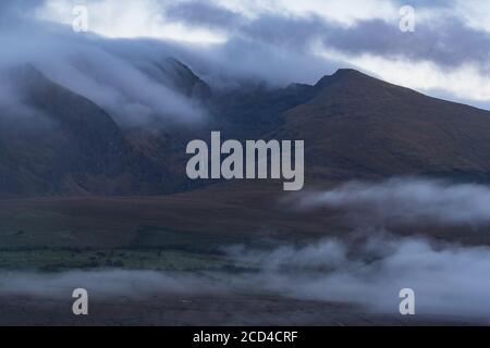 Dramatic clouds and morning mist moving over scenic landscape on the dingle peninsula at dawn, wild Atlantic way in county Kerry, Ireland Stock Photo