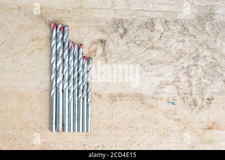 Set of drills of different size on a wooden background. Top view Stock Photo