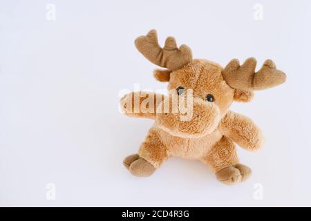 Soft brown deer isolated on white background with natural shadow. Xmas deer soft baby toy. Christmas buck with muffler on white bg. Stock Photo