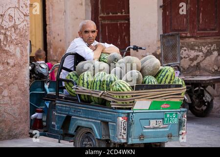 Uyghur street vendor selling watermelons in the city Kashgar / Kashi / Kasjgar, Xinjiang, China Stock Photo