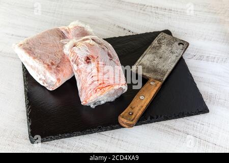 Frozen raw pork neck chops meat steak isolated on slate. Frozen uncooked slices of beef steaks, tenderloin or rib eye with ice crystals on it. Stock Photo
