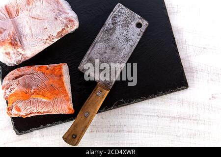 Frozen raw pork neck chops meat steak isolated on slate. Frozen uncooked slices of beef steaks, tenderloin or rib eye with ice crystals on it. Stock Photo