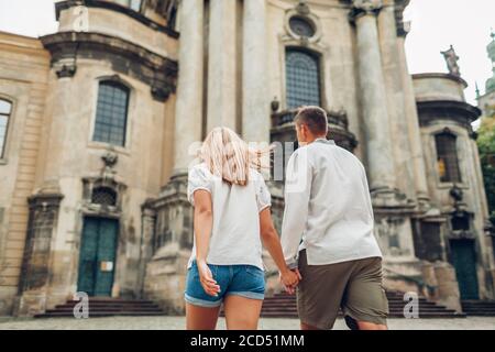 Man and woman in love walking in old Lviv city by dominican cathedral wearing traditional ukrainian shirts.