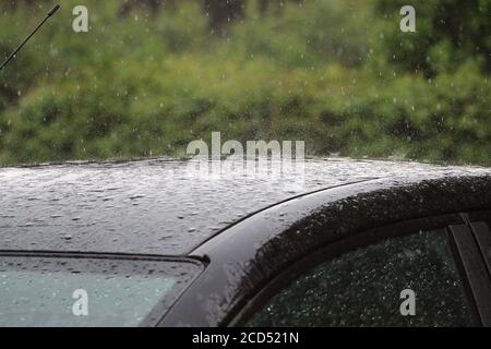 Shallow focus shot of heavy raindrops falling on a car Stock Photo