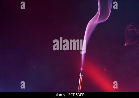 Closeup of a burning incense under the lights against a blurry background Stock Photo