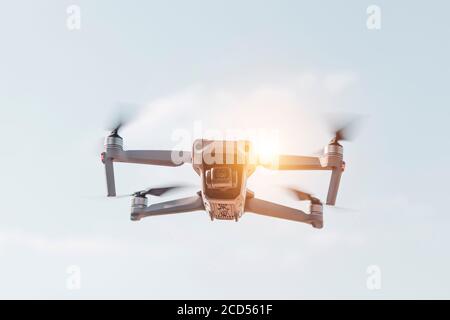 Drone with digital camera flying on sunny sky. Modern RC quadcopter. Stock Photo