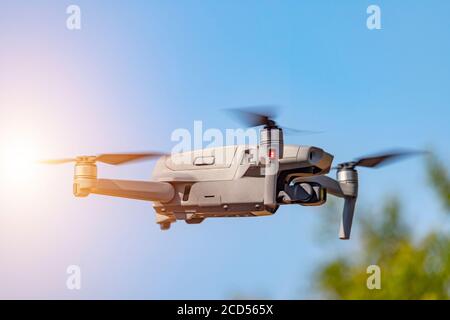 Drone with digital camera flying on sunny sky. Modern RC quadcopter. Stock Photo