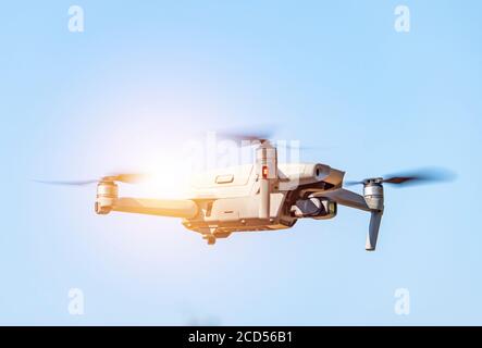 Drone with digital camera flying on sunny sky. Modern RC quadcopter. Stock Photo