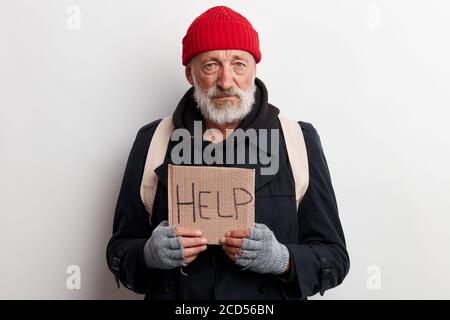 Homeless man holding sign, request for help, seeking help posing at studio over white background Stock Photo