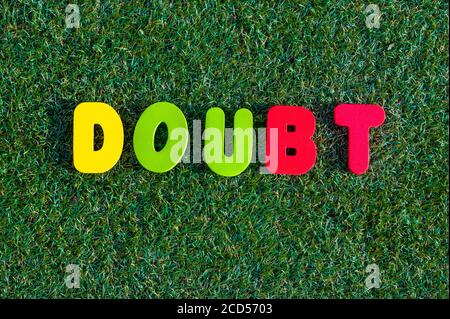 Capital letter "Doubt" word from colorful of wood on grass background. Stock Photo