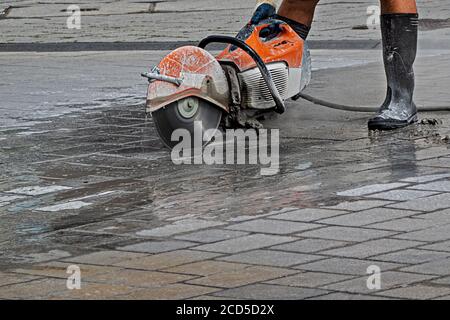man working in rubber boots with a power cutter on the street Stock Photo
