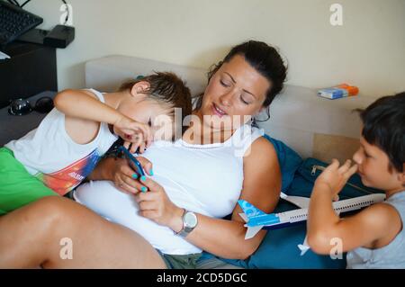 POZNAN, POLAND - Aug 22, 2020: Woman and child sitting on a sofa and using a smartphone together Stock Photo