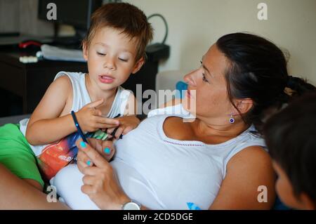 POZNAN, POLAND - Aug 22, 2020: Woman and child sitting on a sofa and using a smartphone together Stock Photo