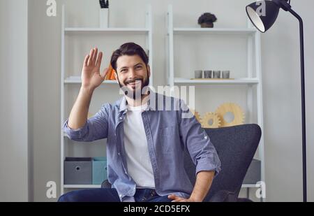 Happy guy looking at camera and waving during online video call from home. Remote communication, work, education Stock Photo