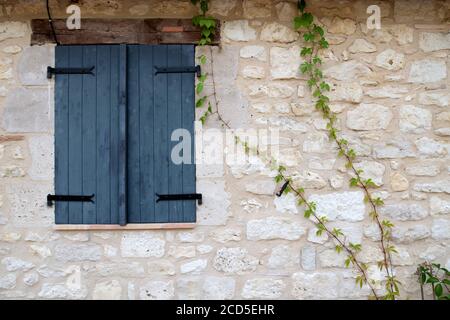 Dark grey window shutters closed in a stone wall surround Stock Photo