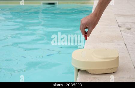 mans hand with contact key used to deactivate swimming pool alarm Stock Photo
