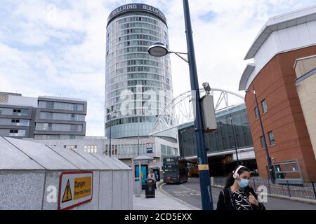 As numbers of Covid-19 cases in Birmingham have increased dramatically in recent weeks, and with the expectation that the city will be added to the watch list of critical areas which may face a local lockdown, people wearing face masks pass near the iconic Rotunda building as they continue to come to the city centre for work and shopping on 18th August 2020 in London, United Kingdom. With other areas in the Midlands under localised lockdown, people and businesses are being urged to follow the Coronavirus advice for workplace and family life help reduce the risk. Stock Photo