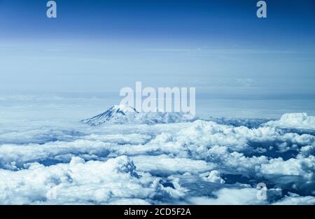 Aerial view of mountain peak rising above clouds