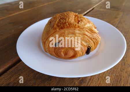 A single pain au chocolat on a white plate Stock Photo