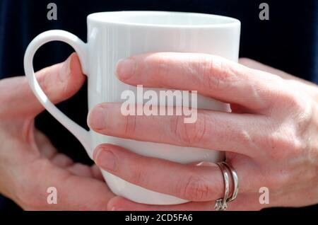 Womans hands holding a white mug of tea or coffee Stock Photo