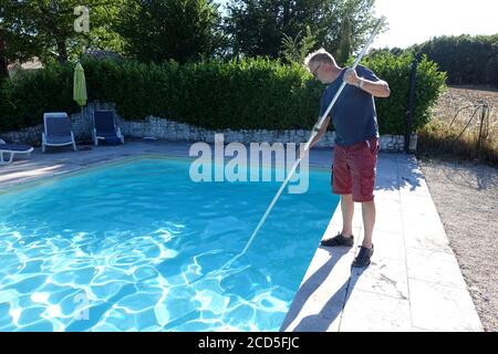 man cleaning a swimming pool with a net Stock Photo