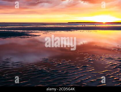 Reflection of pink clouds in the water on the beach during sunset Stock Photo