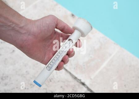 https://l450v.alamy.com/450v/2cd5gbg/mans-hand-holding-a-thermometer-against-background-of-swimming-pool-2cd5gbg.jpg