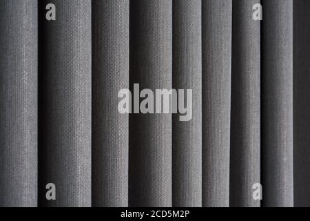 Closeup view of curtain in thin and thick vertical folds made of dense fabric.Textured materials and textiles abstract backgrounds. Stock Photo