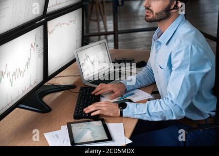 Trader in headset analyzing stat and dynamic on forex charts Stock Photo