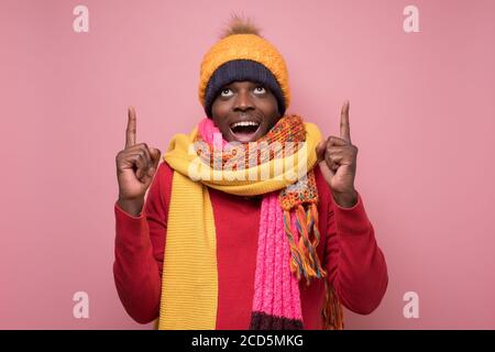 African young man in winter clothes pointing a finger upwards Stock Photo