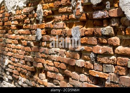Dilapidated with potholes old brick wall of the building, made of red brick, close up. Background or texture. Stock Photo