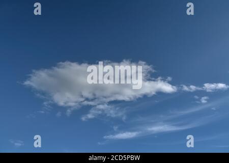 Lonely white cumulus cloud in a blue spring sky. Nature background. Stock Photo
