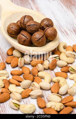 Close-up of Macadamia nuts in a wooden spoon on a wooden background. Various varieties of nuts on a wooden table. Stock Photo