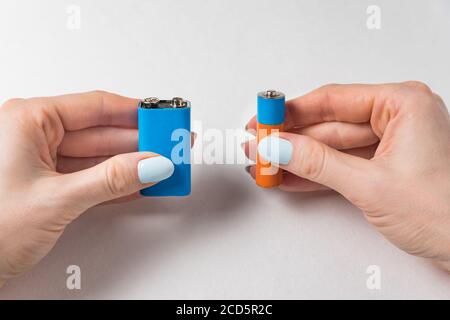 Female hands two batteries on a white background. Generic AA and PP3 battery and accumulator. Stock Photo