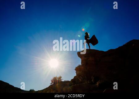Woman silhouette on rock, Aztec Sandstone, Valley of Fire State Park, Mohave Desert, Overton, Nevada, USA Stock Photo
